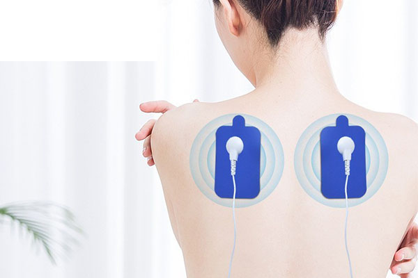 A person applying a TENS unit to their lower back
