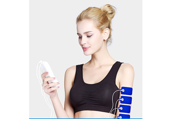 A person holding a small, portable Mini TENS device in their hand