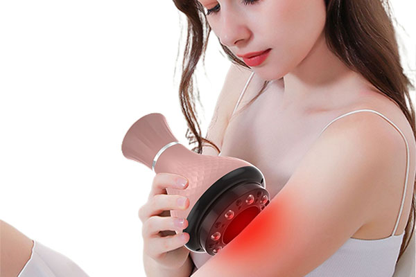 A person looking relaxed while using an electric gua sha tool on their shoulder